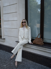 a lady wears a beige tweed boxy crop jacket with white pants